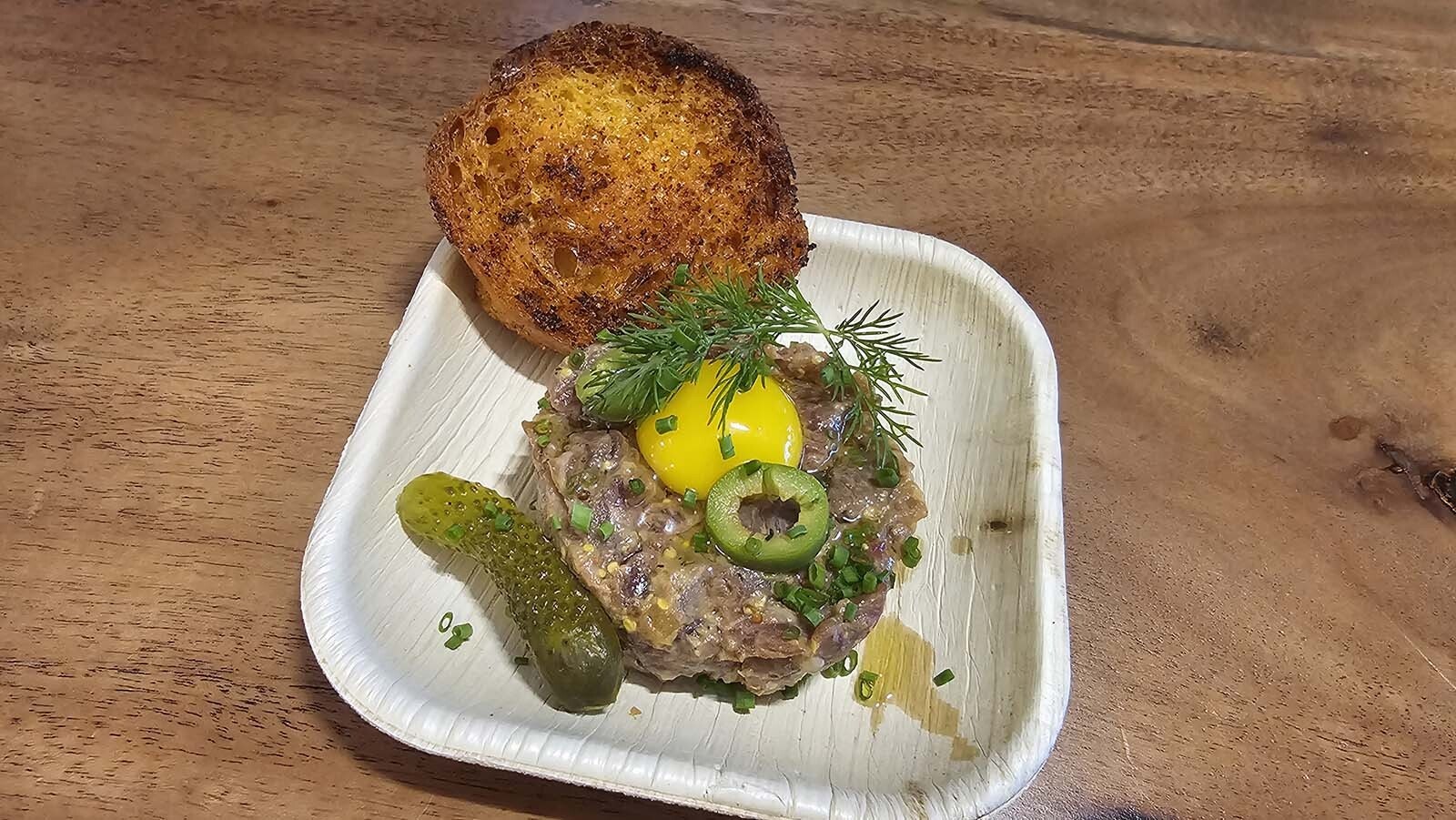 Steak tartare topped with a quail egg and garnished with dill, accompanied by toast. The dish was served during Chef Petrina Peart's "Yes Chef!" Watch Party.